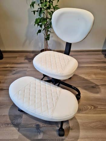 Ergonomic white cushioned chair and footrest on a wooden floor, ideal for comfort-focused home office shopping
