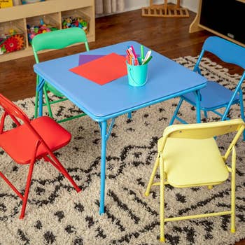 Children's playroom array acceptable with bluish table, reddish and yellowish chairs, and crafting supplies connected a patterned rug