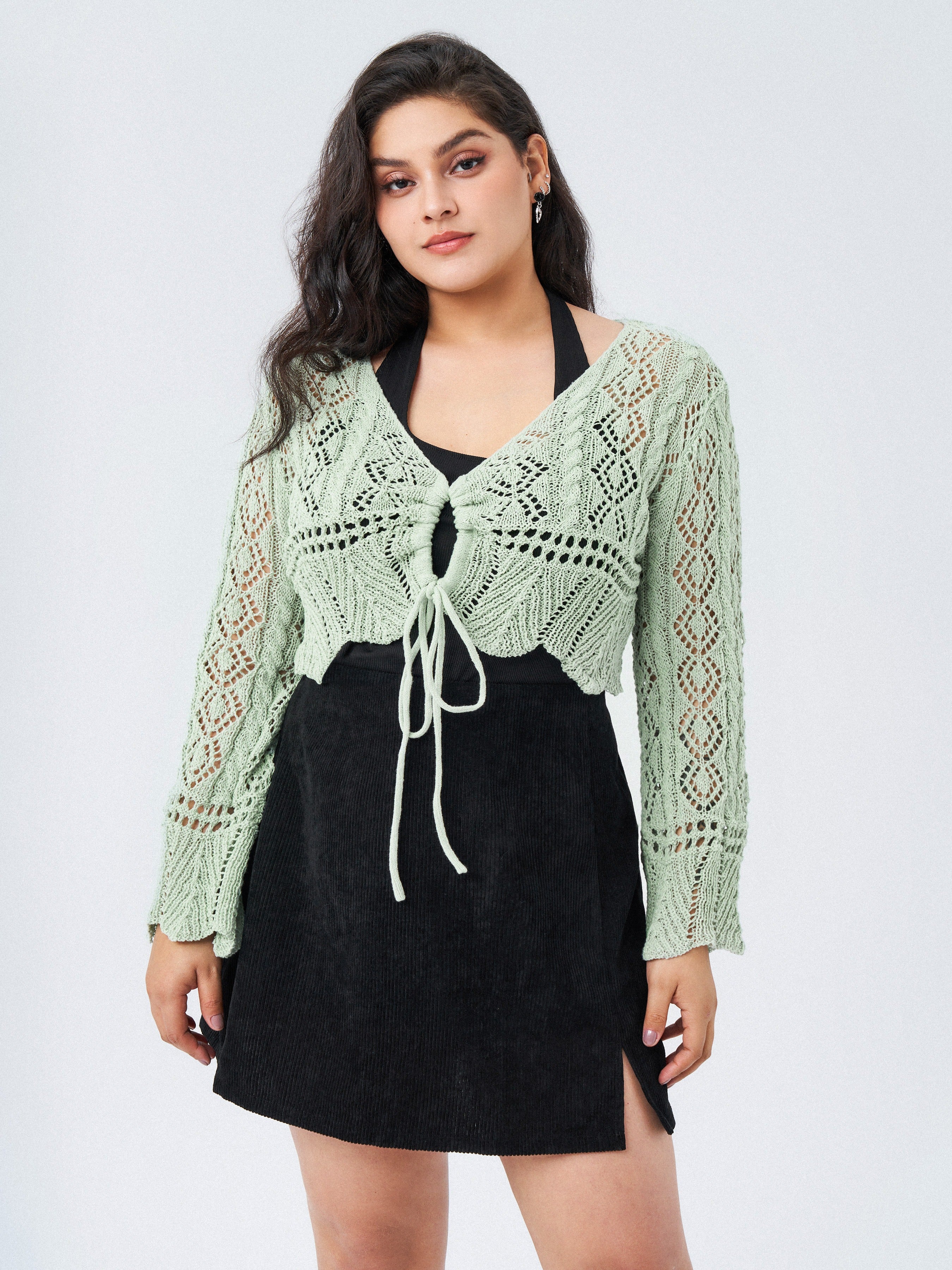 model wearing a mint green cropped long-sleeve crochet cardigan with a tie front detail