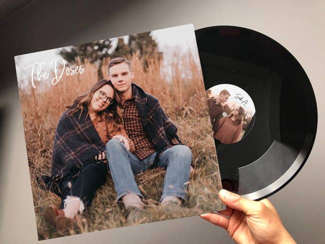 Hand holding a vinyl record with a personalized photo label alongside its album cover