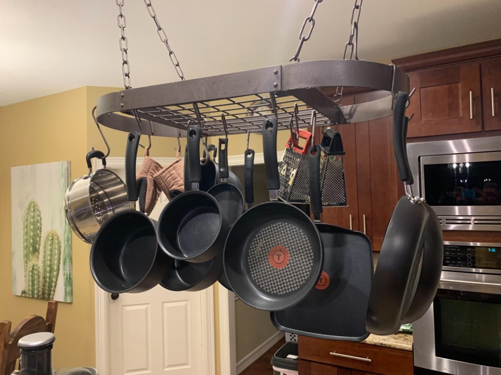 Hanging rack with assorted  pots and pans organized successful  a kitchen, showcasing cookware retention  options