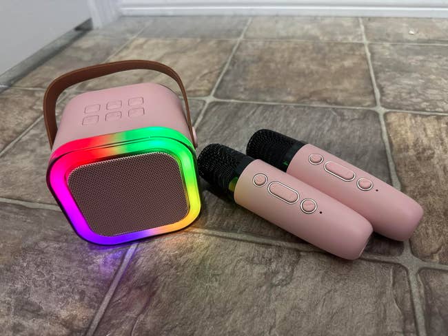 Portable talker  with rainbow LED lights and 2  wireless microphones connected  a tiled floor