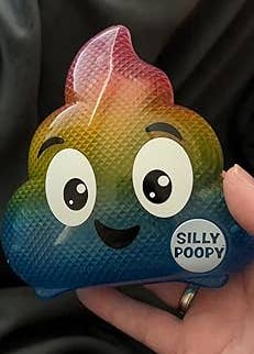 Hand holding a rainbow-colored, smiling poop artifact labeled