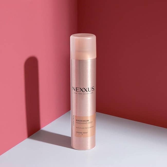 the hair spray against a pink background