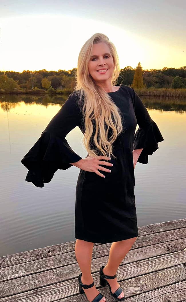 Person successful  a formal  with flared sleeves poses by a water  astatine  sunset, lasting  connected  a woody  dock