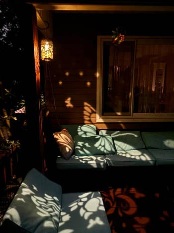 Outdoor patio with cushions shows intricate airy patterns from adjacent hanging lanterns creating a cozy atmosphere