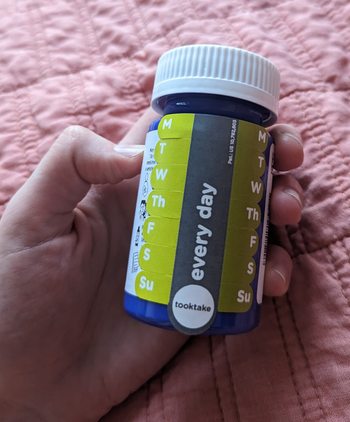 a reviewer holding a pill bottle with the tracking stickers applied 
