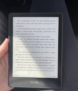 reviewer holding the kindle while reading a page from a book