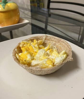 A waffle bowl full of eggs on a plate 