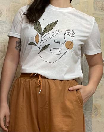 reviewer wears a white t-shirt with a drawn portrait on it