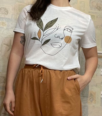 reviewer wears a white t-shirt with a drawn portrait on it