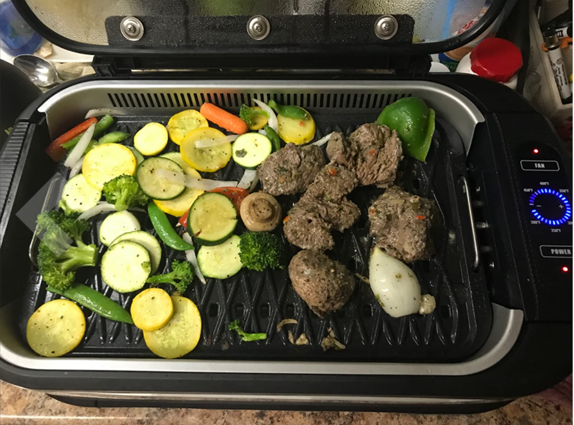 Reviewer's small black grill with meat and veggies on top