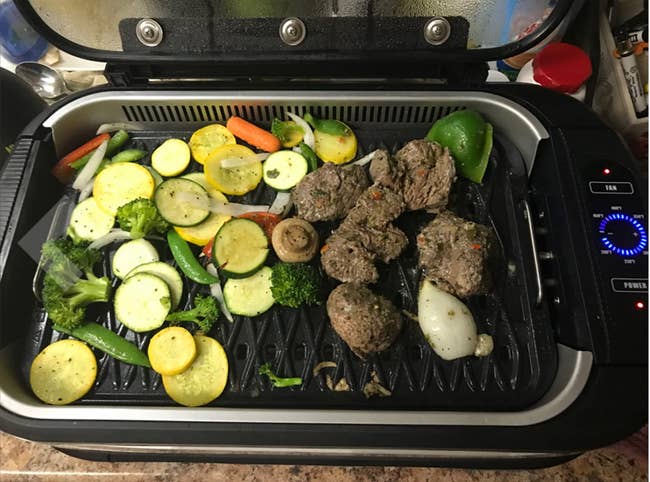 Reviewer's small black grill with meat and veggies on top 