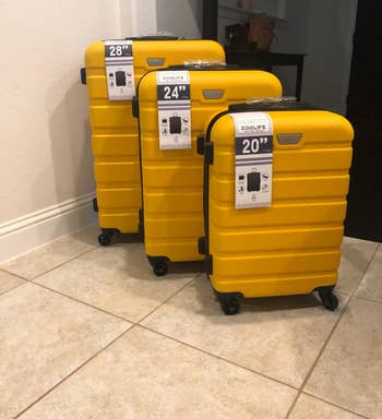 Reviewer photo of the three piece luggage set in a bright yellow color