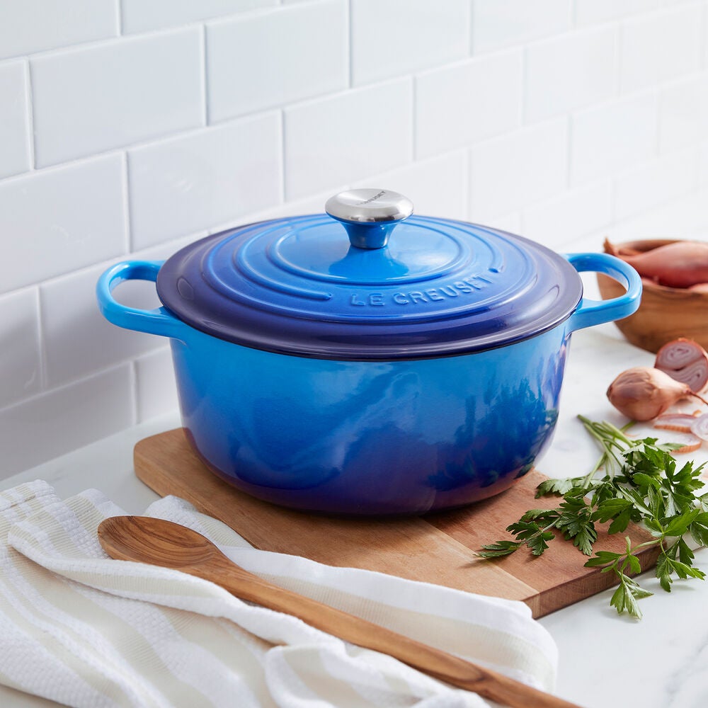 the navy blue dutch oven sitting on a cutting board