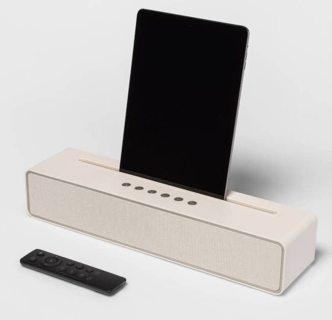 the beige speaker holding a phone