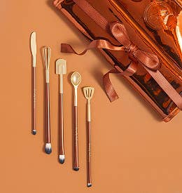 the brown and gold brushes with ends that look like a knife, whisk, spatula, spoon, and slotted turner