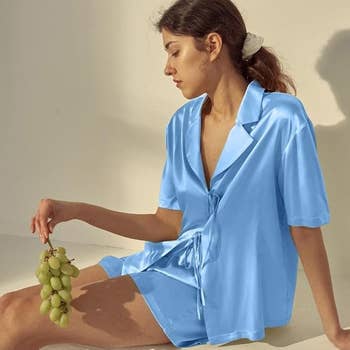 Woman successful  silky pajama acceptable   holding grapes, seated against a airy  background