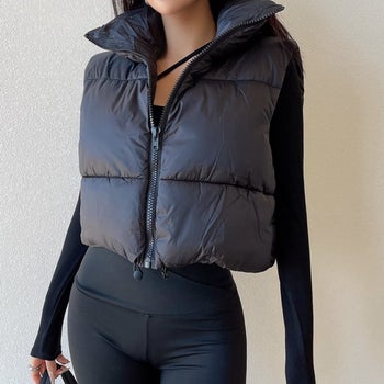 model wearing the black cropped puffer vest over a black top with black pants