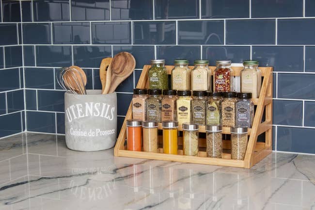 the three-tier bamboo spice rack on a kitchen counter holding spice jars