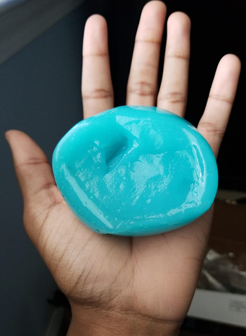 reviewer's hand holding the blue cleaning gel