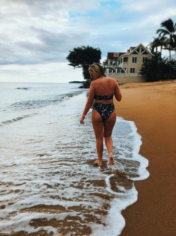 a reviewer walking along the beach in the black marbled bathing suit