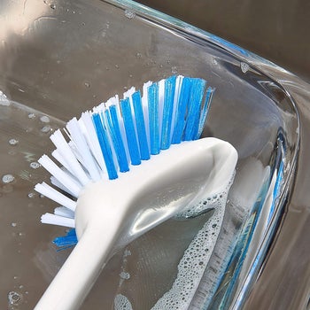 close up of the brush's scraper edge cleaning a glass dish