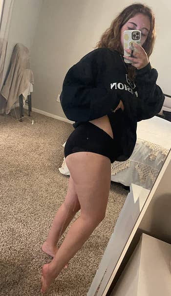 side view of reviewer wearing the black underwear with a sweatshirt