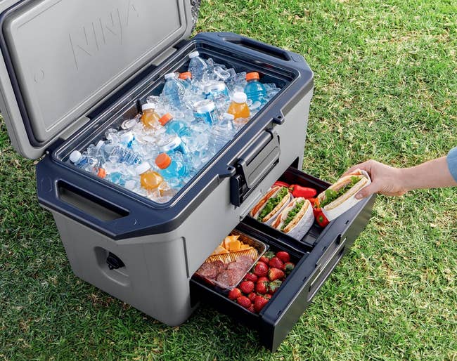the open cooler with drinks in ice on top and sandwiches and snacks in the bottom drawer