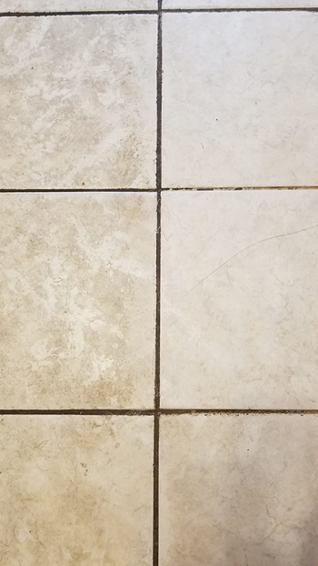 a reviewer photo of tiles that are dirty on the left side and clean on the right 
