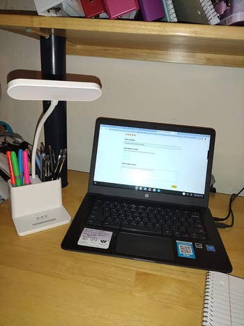 Reviewer's white LED desk lamp on their desk filled with pens and highlighters, next to their laptop