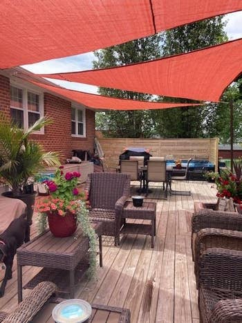 Patio with wicker furniture, plants, and a grill under three of the sunshade triangles