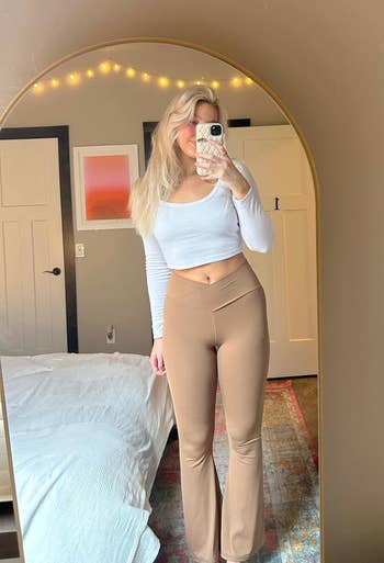 reviewer in a mirror selfie wearing a long-sleeve crop top and light brown flared pants