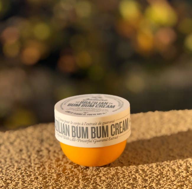 Jar of Brazilian Bum Bum Cream on a textured surface, with blurred background