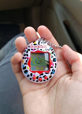 reviewer holding the tamagotchi in their hand
