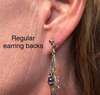 Tampilan jarak dekat dari telinga seseorang yang mengenakan anting menjuntai dengan anting standar di bagian belakang. Teks berbunyi: