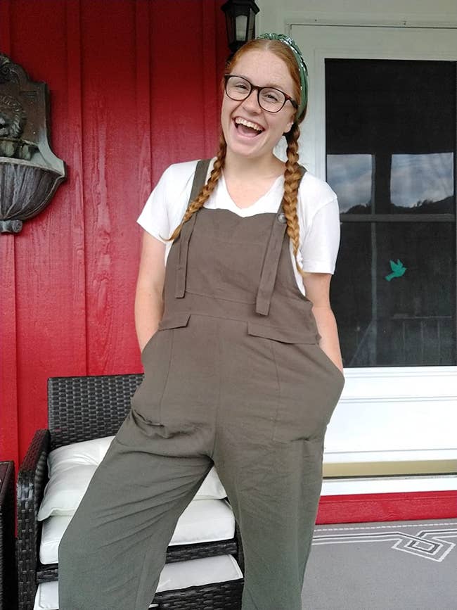 reviewer wearing gray baggy overalls with a plain white tee underneath