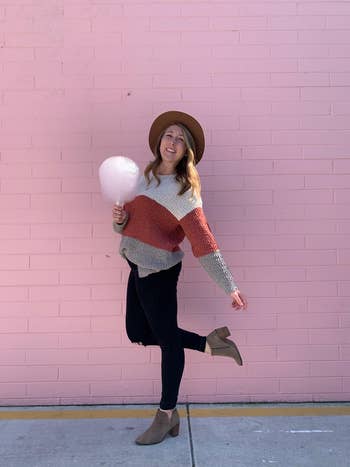 a reviewer in a color block version of the sweater in front of a pink brick wall