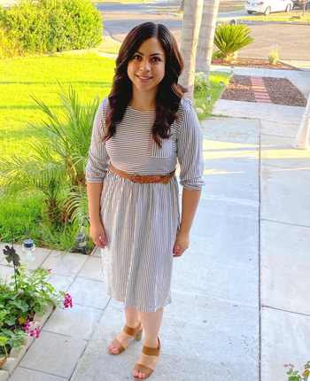 reviewer wearing the dress with a tan belt and sandals