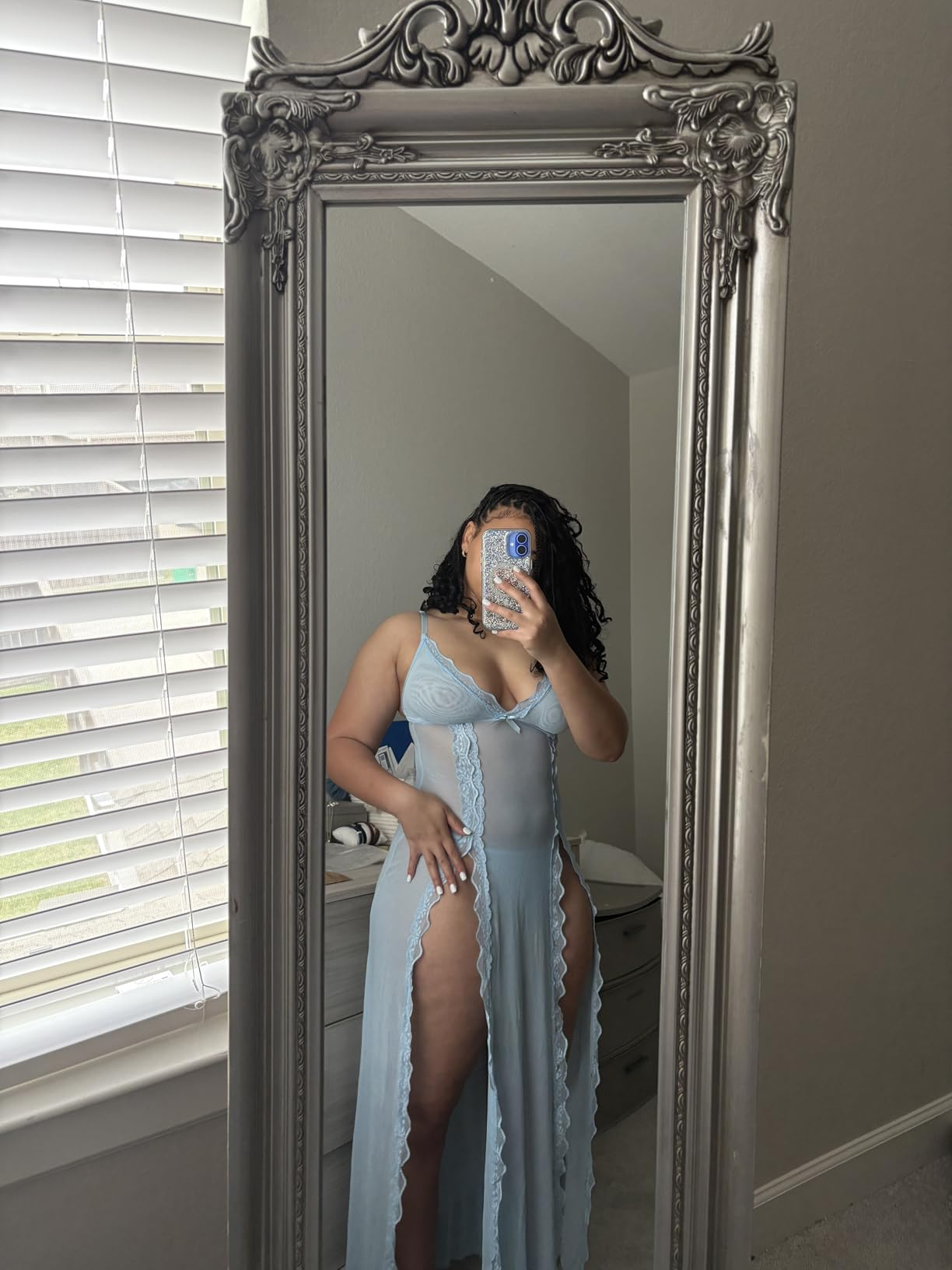 A idiosyncratic   takes a reflector  selfie wearing a sheer nightgown with lace details, lasting  successful  a country   with blinds partially open