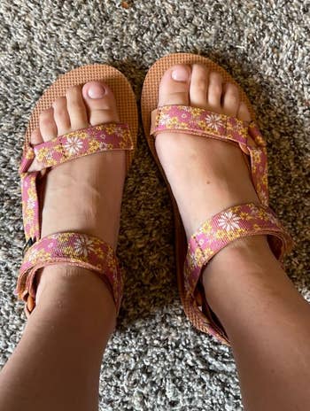 a reviewer wearing the sandals featuring a floral print