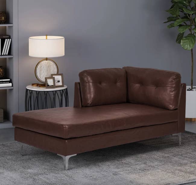 the dark brown faux leather chaise in a living room