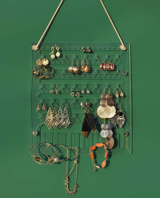 the clear holder holding earrings while hanging on a green wall