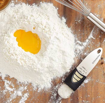 the measuring spoon filled with salt next to a pile of flour and a whisk