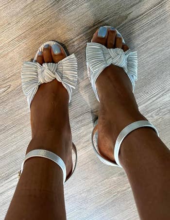 Stylish strappy sandals with ample bows connected toes, worn connected a woody floor