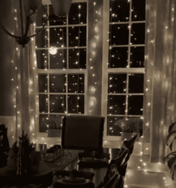 reviewer gif of the twinkling lights hung up in front of windows in their dining room