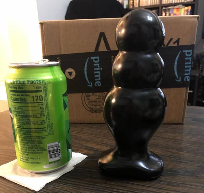 Black rippled butt plug next to soda can for size comparison