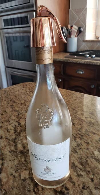 A bottle of rosé with a metallic rose stopper with a lever on it 
