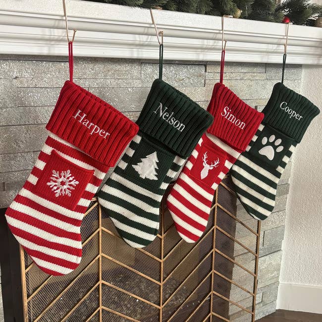 Four personalized striped Christmas stockings labeled Harper, Nelson, Simon, and Cooper hang on a fireplace, featuring festive designs
