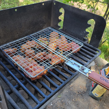 reviewer photo of the grill basket filled with meat on a charcoal grill